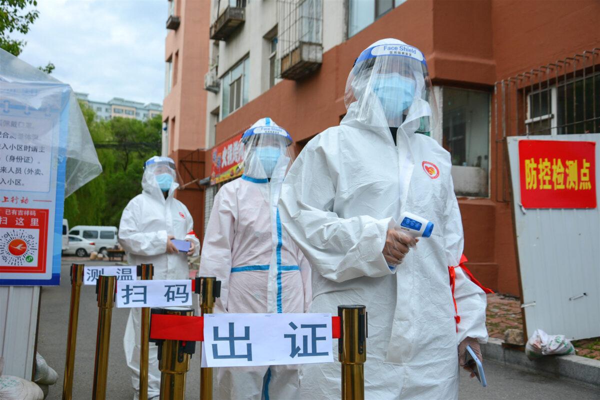 Staff are waiting to check people’s entry permits, screen their body temperature, and scan their health codes at the entrance of a residential compound in Jilin City, China, on May 25, 2020. (STR/AFP via Getty Images)