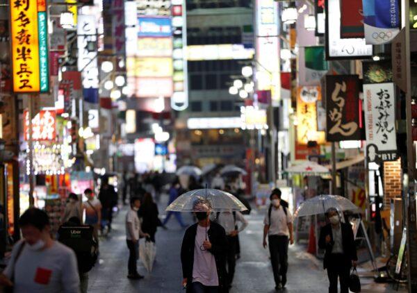 People wearing protective face masks, following the outbreak of the CCP virus, walk in the Kabukicho entertainment district, on the first day after the Japanese government lifted the state of emergency in Tokyo, on May 26, 2020. (Issei Kato/Reuters)