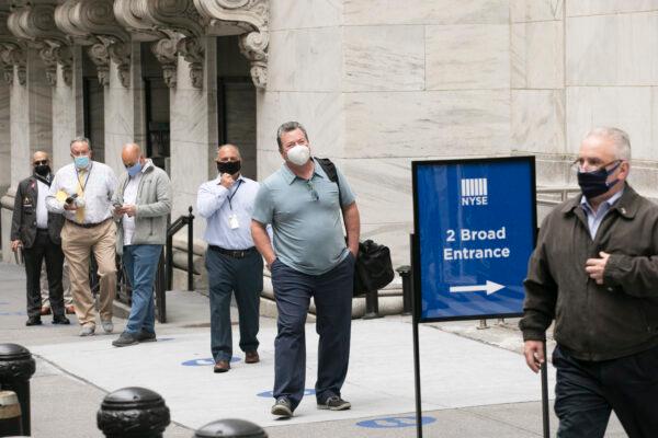 New York Stock Exchange employees wait to enter the building as the trading floor partially reopens, in New York City, on May 26, 2020. (Mark Lennihan/AP Photo)