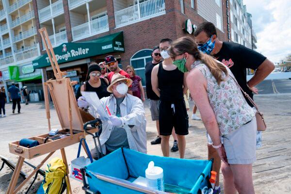 A local artist and onlookers wear masks on the boardwalk during the Memorial Day holiday weekend in Ocean City, Md., on May 23, 2020. (Alex Edelman/AFP via Getty Images)