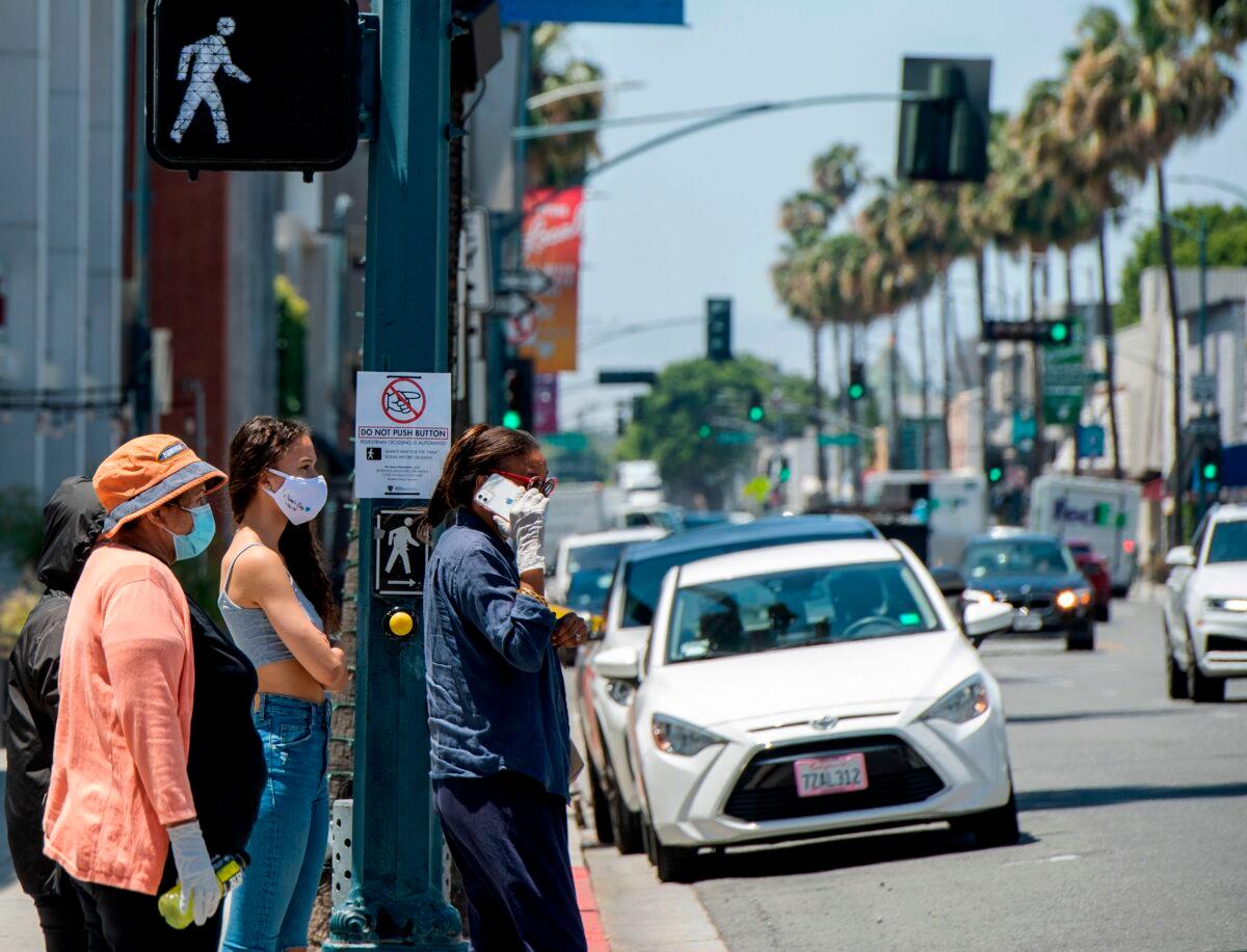 People wait to cross the street on Rodeo Drive, where a sign is displayed asking the pedestrian not to push the button, amid the COVID- 19 pandemic in Beverly Hills, Calif., May 26, 2020 (Valerie Macon/AFP via Getty Images)