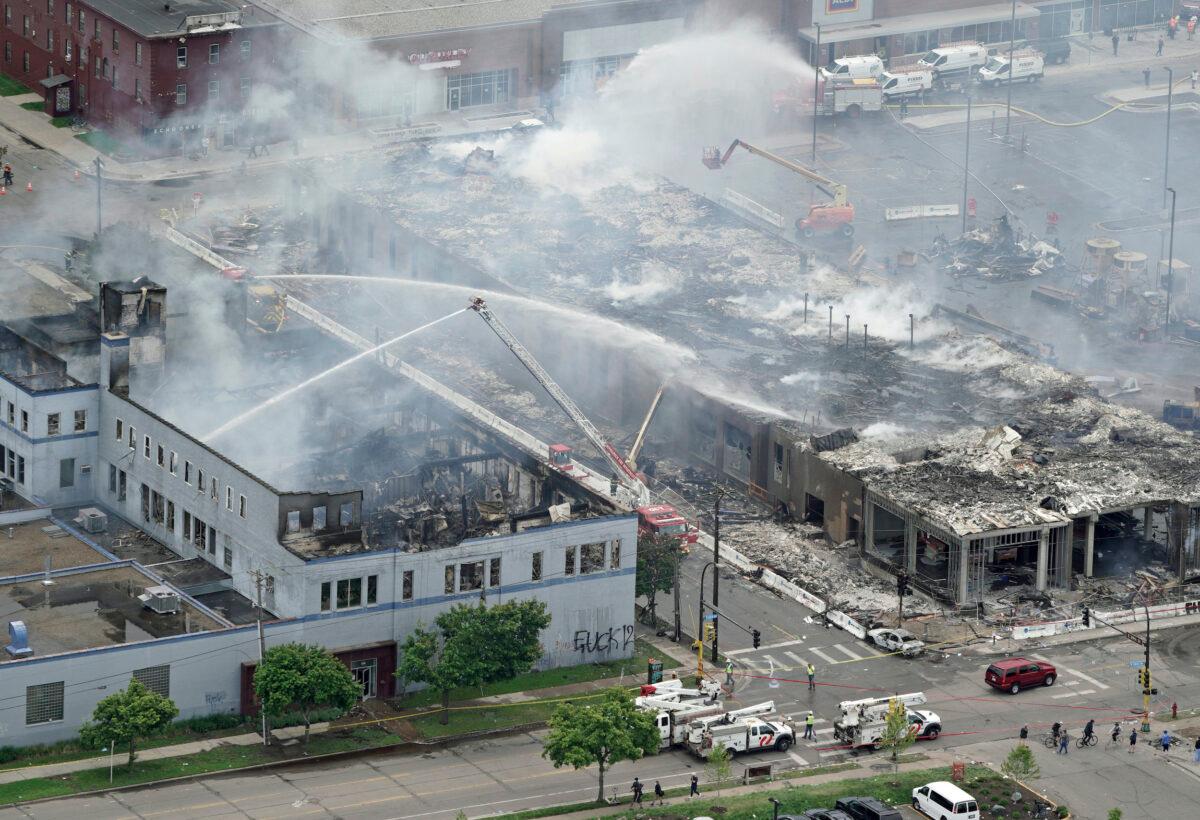 Firefighters work on an apartment building under construction on May 28, 2020, tentatively known as Midtown Corner, left, after it was burned to the ground in Minneapolis, Minn. during protests. (Brian Peterson/Star Tribune via AP)
