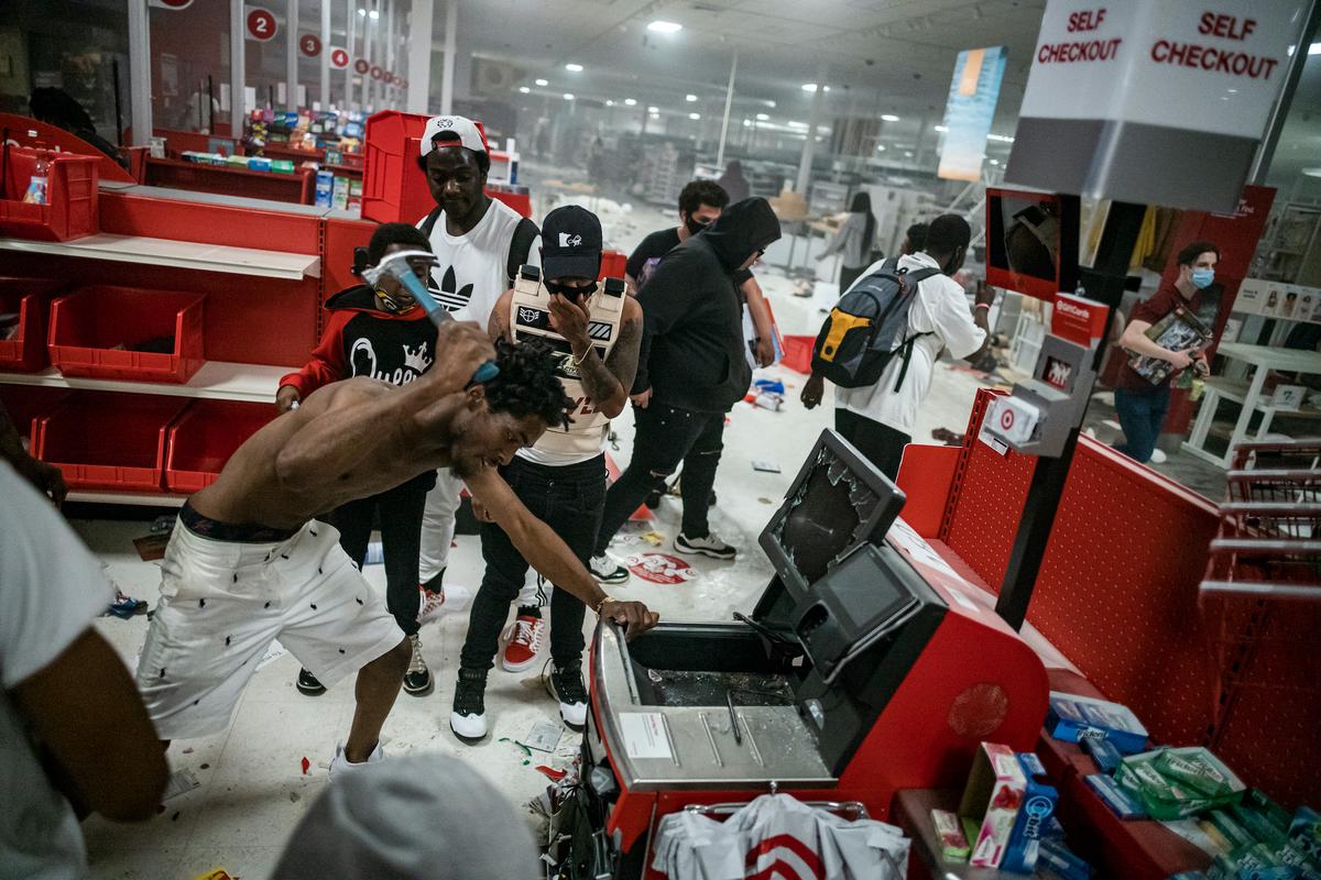 A looter uses a claw hammer as he tries to break in to a cash register at a Target store in Minneapolis, Minn., on May 27, 2020. (Richard Tsong-Taatarii/Star Tribune via AP)
