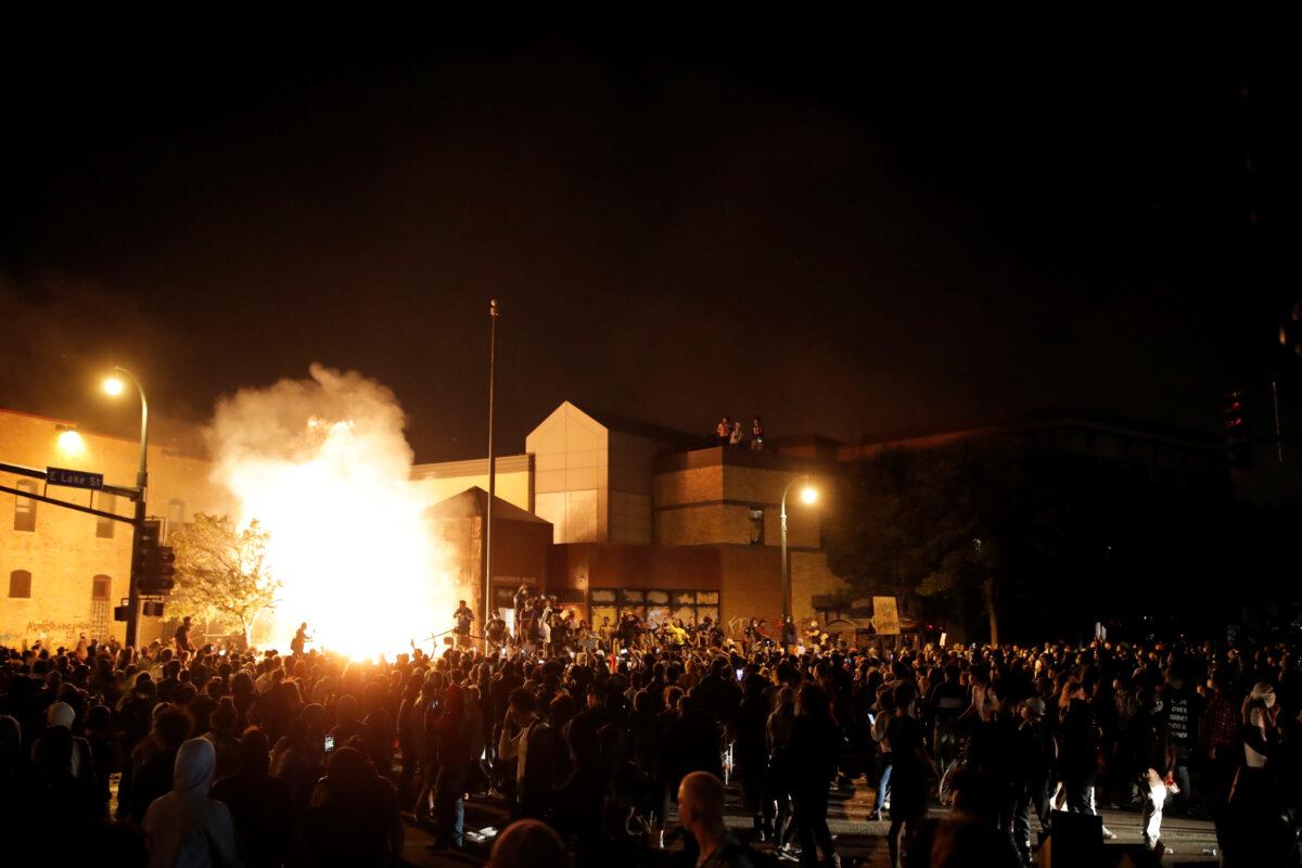 Protesters gather around after setting fire to the entrance of a police station in Minneapolis, Minn., on May 29, 2020. (Carlos Barria/Reuters)