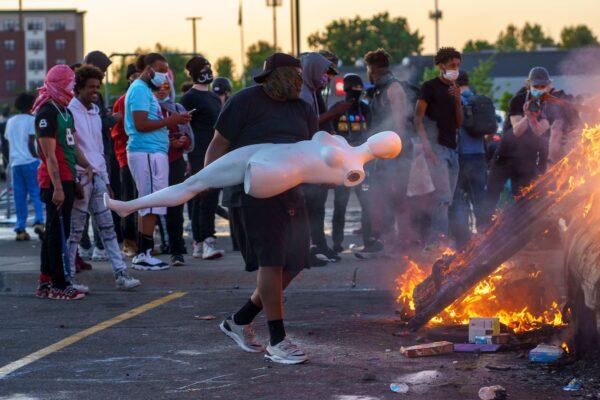 A protester throws a mannequin onto a burning car outside a Target store near the Third Police Precinct in Minneapolis, Minnesota, on May 28, 2020. (Kerem Yucel/AFP via Getty Images)
