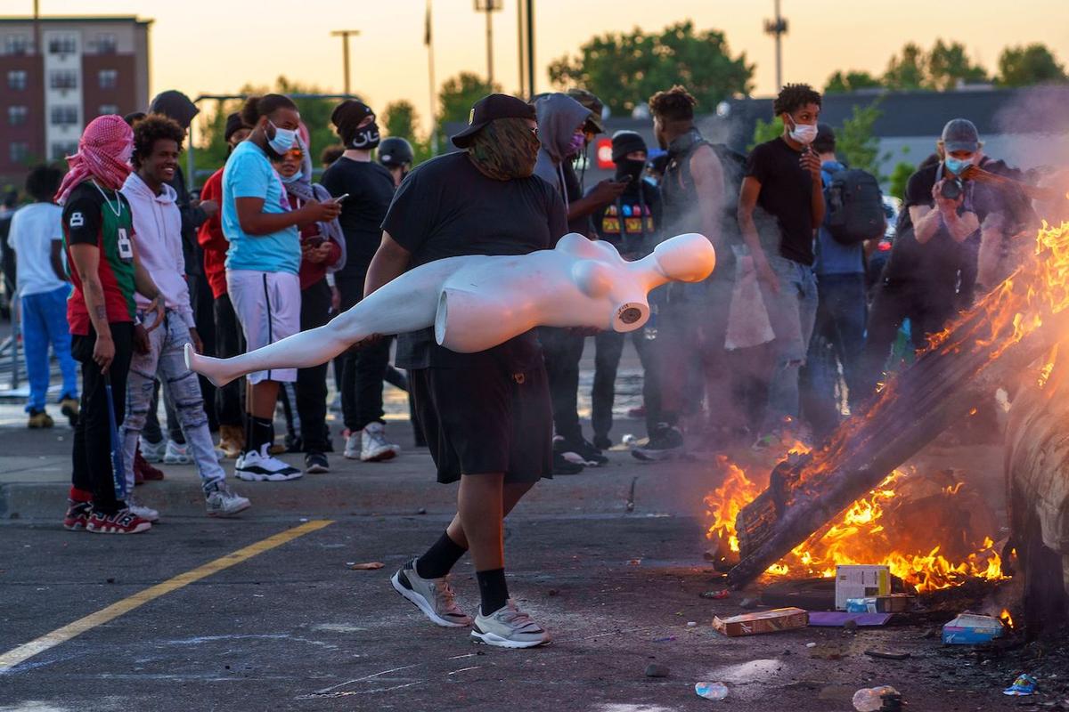 A protester throws a mannequin onto a burning car outside a Target store near the Third Police Precinct in Minneapolis, Minn., on May 28, 2020. (Kerem Yucel/AFP via Getty Images)
