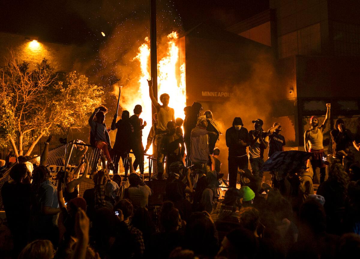 Rioters cheer as the Third Police Precinct burns behind them in Minneapolis, Minn., on May 28, 2020. (Stephen Maturen/Getty Images)