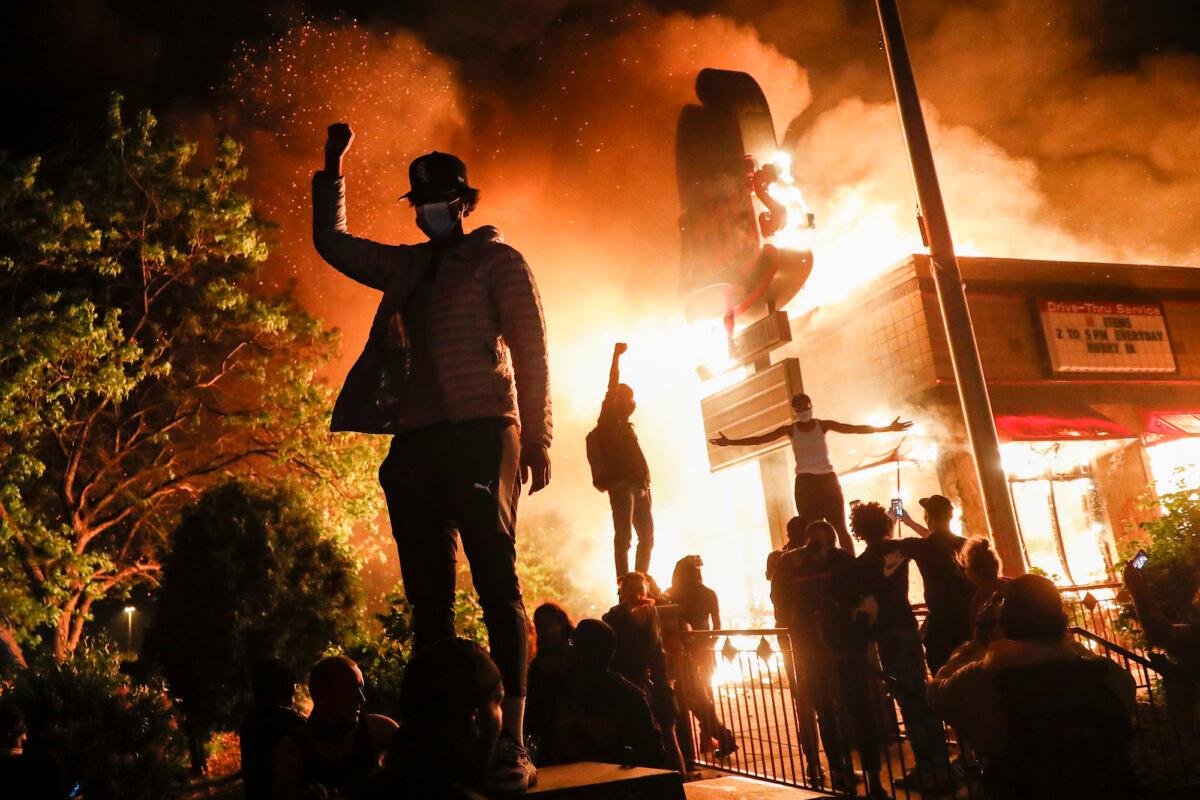 Protesters demonstrate outside a burning fast food restaurant, in Minneapolis, Minn., on May 29, 2020. (John Minchillo/AP Photo)