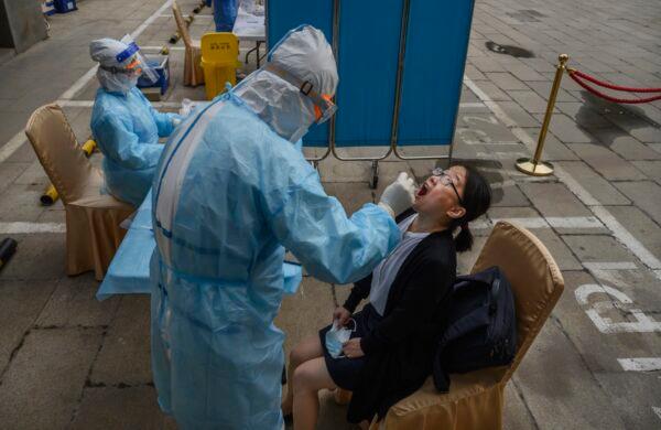 A Chinese health worker carries out a nucleic acid test on a journalist covering events around the National People's Congress in Beijing on May 28, 2020. (Kevin Frayer/Getty Images)