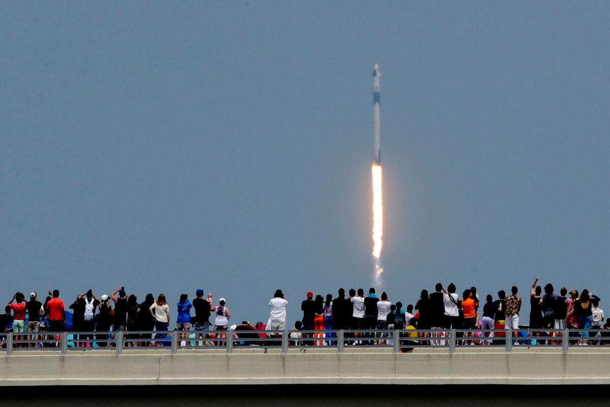 Spectators watch from a bridge in Titusville, Fla., as SpaceX Falcon 9 lifts off with NASA astronauts Doug Hurley and Bob Behnken in the Dragon crew capsule, from the Kennedy Space Center at Cape Canaveral, Fla., on May 30, 2020. (Charlie Riedel/AP photo)