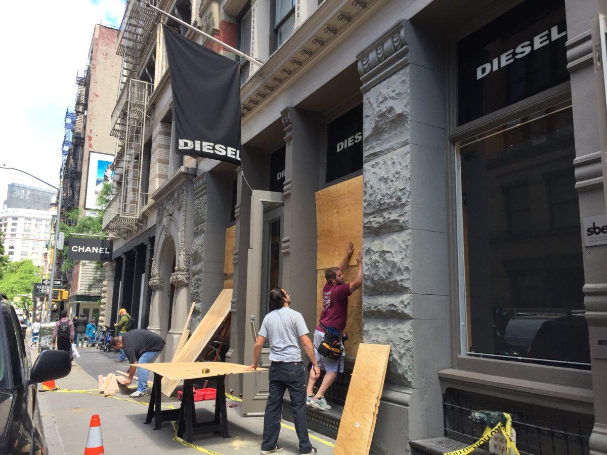 Workers boarding the damaged display windows of Diesel store in SoHo shopping district of lower Manhattan, N.Y., on June 1, 2020. (Venus Upadhayaya/The Epoch Times)