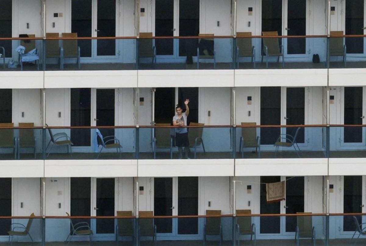 A crew member waves on the balcony of Italian cruise ship Costa Atlantica, which has crew members confirmed with cases of the CCP virus infection, in Nagasaki, southern Japan, on April 26, 2020. (Kyodo/via Reuters/File Photo)