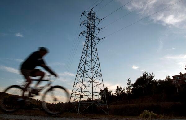 A cyclist rides past high-tension power lines in Mill Valley, Calif., during a statewide blackout on Oct. 10, 2019. (Josh Edelson/AFP via Getty Images)