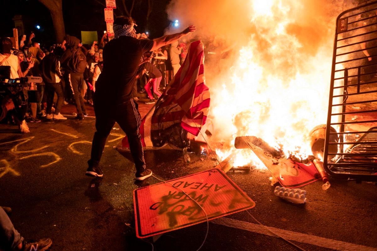 A protester throws a U.S. flag into a burning barricade during protests and riots in Washington on May 31, 2020. (Roberto Schmidt/AFP via Getty Images)