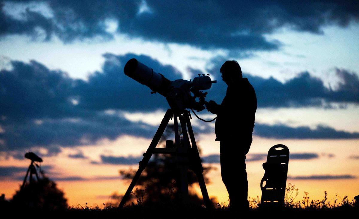A man stands in front of his telescope as he attends with other people for the partial lunar eclipse over Vienna, on July 16, 2019. (GEORG HOCHMUTH/AFP via Getty Images)