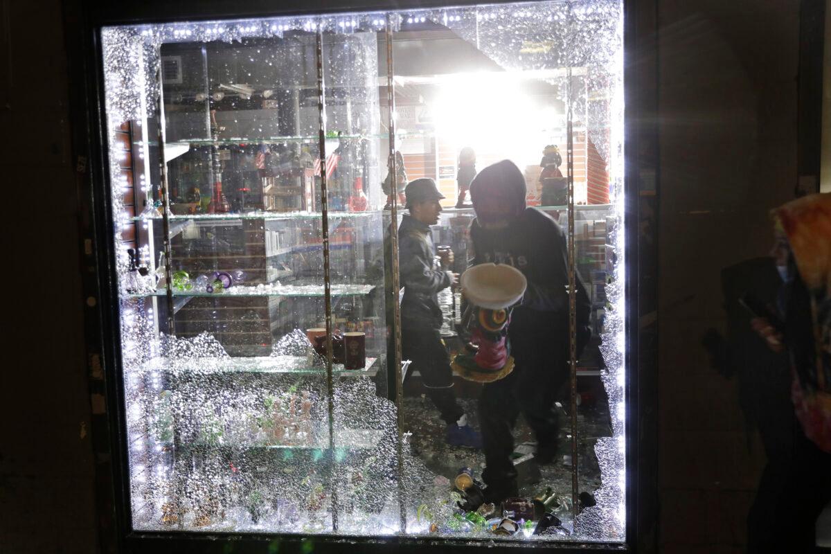 People carry things out of a smoke shop through a broken window in New York City, on June 1, 2020. (Seth Wenig/AP Photo)