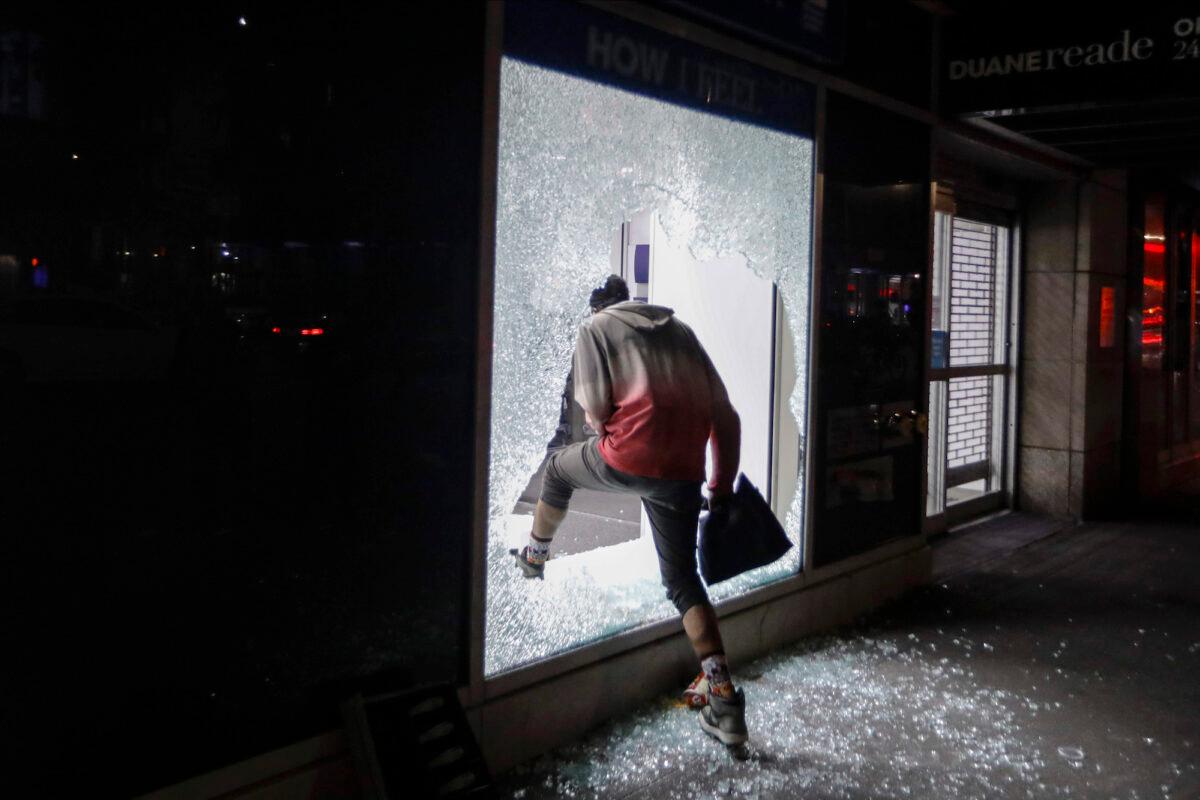 A person enters a store through a broken window, in New York City on June 1, 2020. (Frank Franklin II/AP Photo)