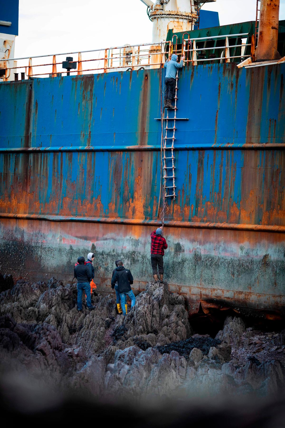 Locals climb aboard the "ghost ship" MV Alta. (CATHAL NOONAN/AFP via Getty Images)
