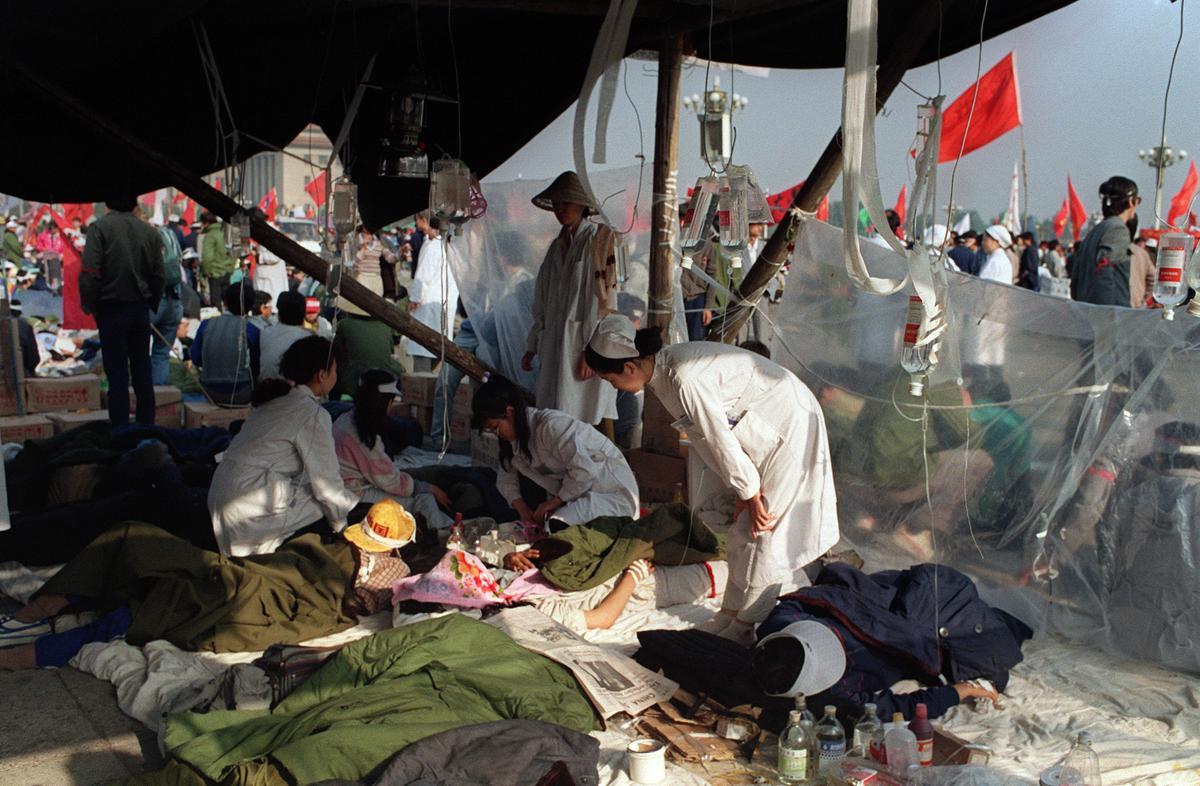 Ailing student hunger strikers from Beijing University receive first aid treatment under a makeshift tent set up on May 17, 1989, at Tiananmen Square as students enter the 5th day of a marathon hunger strike as part of a mass pro-democracy protest against the Chinese regime. (Catherine Henriette/AFP via Getty Images)