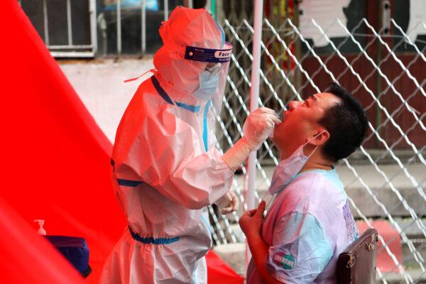 A medical worker takes a swab sample from a resident to be tested for the CCP virus on a street in Mudanjiang, China on June 3, 2020. (STR/AFP via Getty Images)