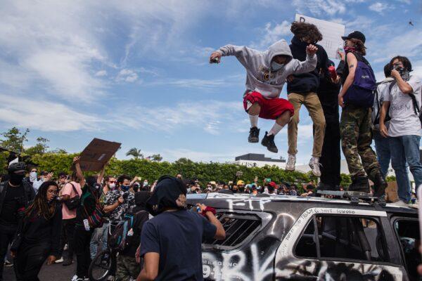Demonstrators jump on a damaged police vehicle in Los Angeles on May 30, 2020, during a protest against the death of George Floyd. (Ariana Drehsler/AFP via Getty Images)
