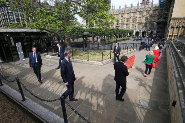  UK lawmakers including Leader of the House of Commons Jacob Rees-Mogg, center left, queue outside the Houses of Commons in Westminster, London, on June 2, 2020. (Jonathan Brady/PA via AP)
