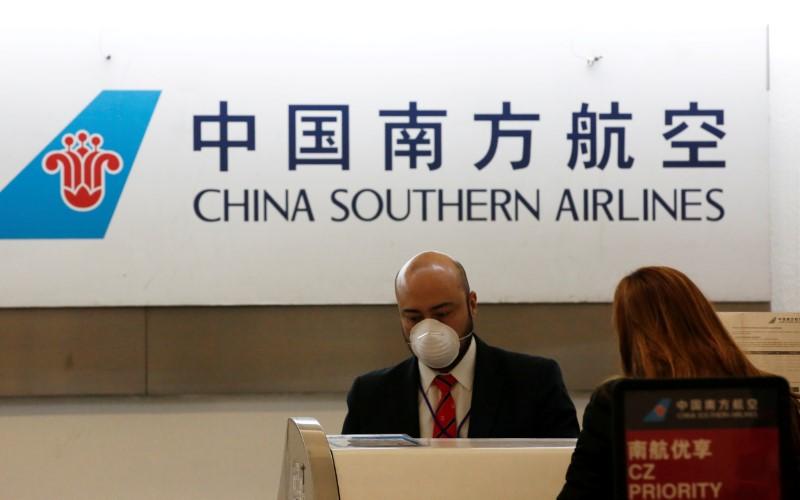 A China Southern Airlines employee wears a surgical mask as a preventive measure in light of the coronavirus outbreak in China, while he attends a customer behind the counter at Benito Juarez international airport in Mexico City, Mexico, on Jan. 28, 2020. (Carlos Jasso/Reuters)