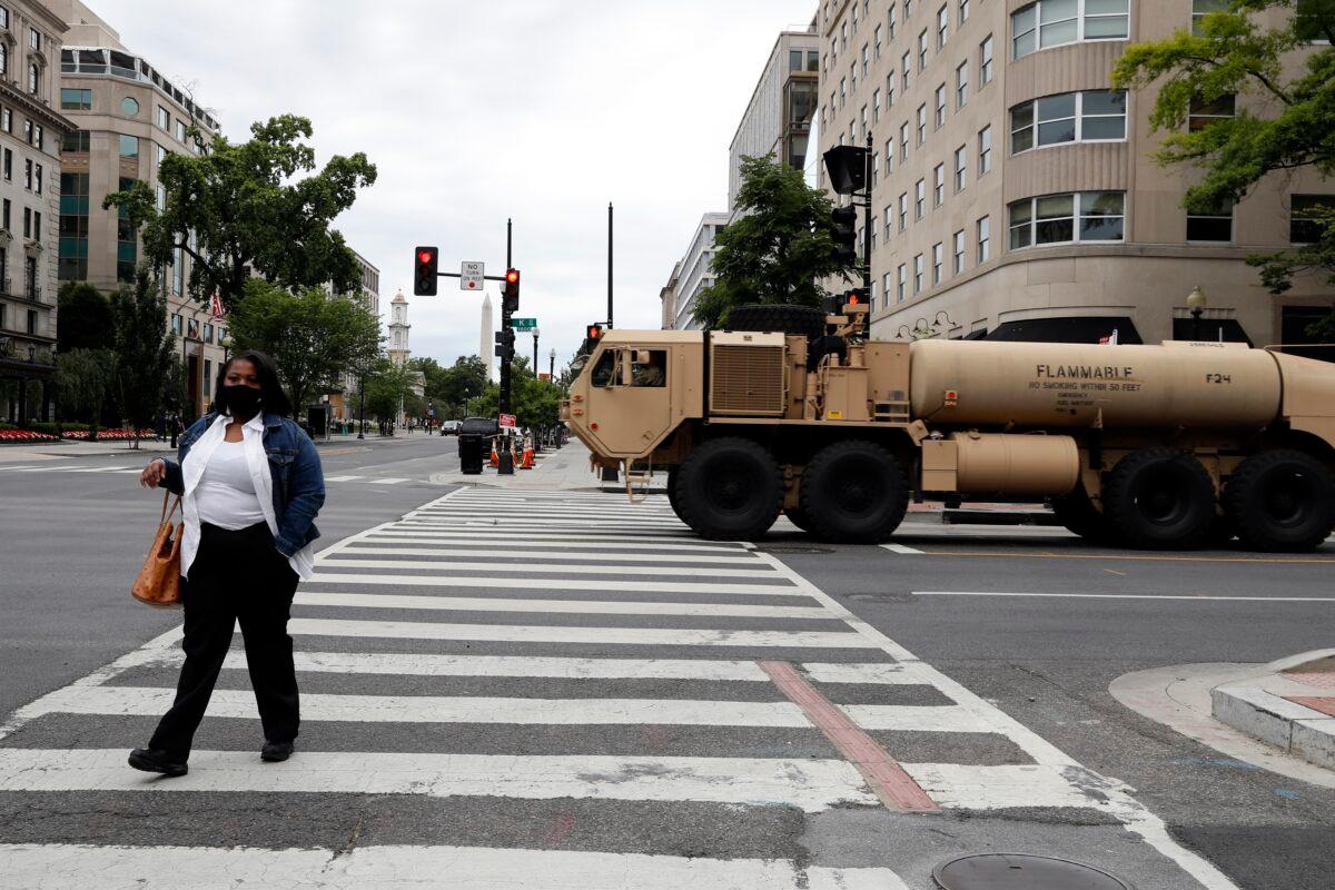 A woman walks across K Street as a military fuel truck passes by as demonstrators continue to protest the death of George Floyd near the White House in Washington on June 2, 2020. (Jacquelyn Martin/AP Photo)