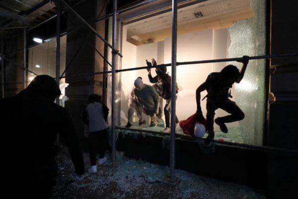A man jumps from the window of a damaged store in New York on June 2, 2020. (Jeenah Moon/Reuters)