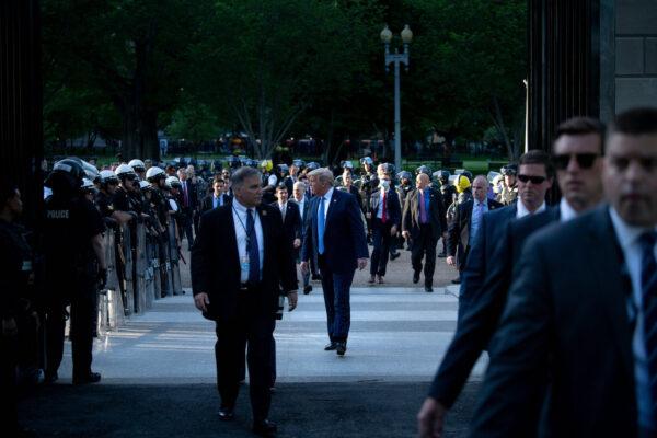 President Donald Trump walks through a colonnade of police in riot gear while walking to the White House from St. John's Church after the area was cleared of people protesting in Washington, on June 1, 2020. (Brendan Smialowski/AFP via Getty Images)
