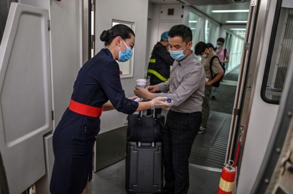 A flight attendant wearing a protective mask checks the body temperature of the passengers next to the door of the plane at the Tianhe Airport in Wuhan, in Chinas central Hubei province on May 29, 2020. (Hector Retamal /AFP via Getty Images)