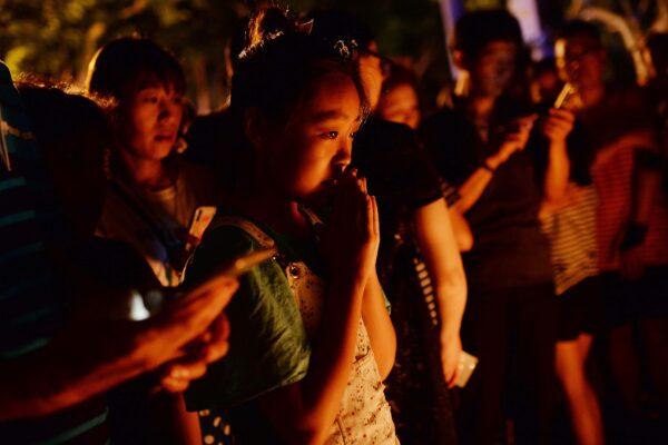 Children and adults pray during a candle-light vigil at the site of a knife attack which left two children dead in Shanghai, China, on June 28, 2018. (-/AFP via Getty Images)