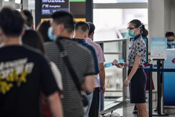 An airline worker wearing a protective mask checks the body temperature of passengers in the boarding area at the Tianhe Airport in Wuhan, in Chinas central Hubei province on May 29, 2020. (Hector Retamal /AFP via Getty Images)