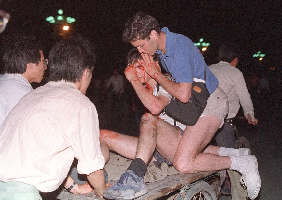 Taken care of by others, an unidentified foreign journalist (2nd-R) is carried out from the site of the clash between the army and students on June 4, 1989, near Tiananmen Square, China. (TOMMY CHENG/AFP via Getty Images)