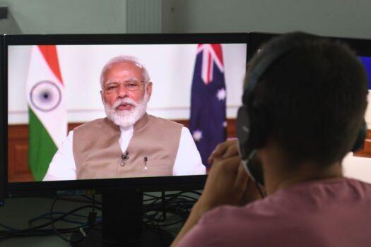 A man wearing a face-mask watches on a monitor Indian Prime Minister Narendra Modi speak during a bilateral virtual summit with Australian Prime Minister Scott Morrison at an office in New Delhi on June 4, 2020. (Prakash Singh/AFP via Getty Images)