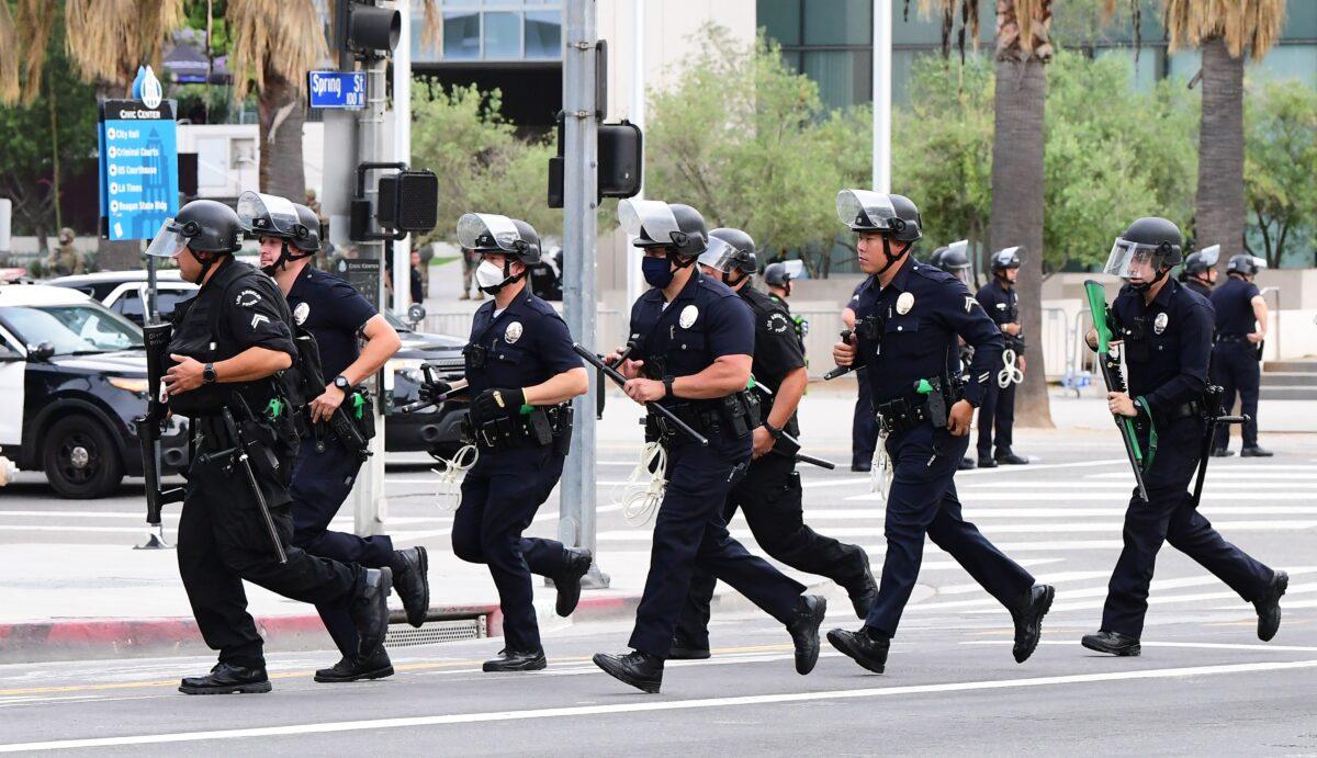 Officers from the Los Angeles Police Department run to formation during a march over the death of George Floyd, an unarmed black man, who died after a police officer kneeled on his neck for several minutes, in front of the Los Angeles City Hall in Los Angeles, Calif. on June 1, 2020. (Frederic J. Brown/AFP via Getty Images)