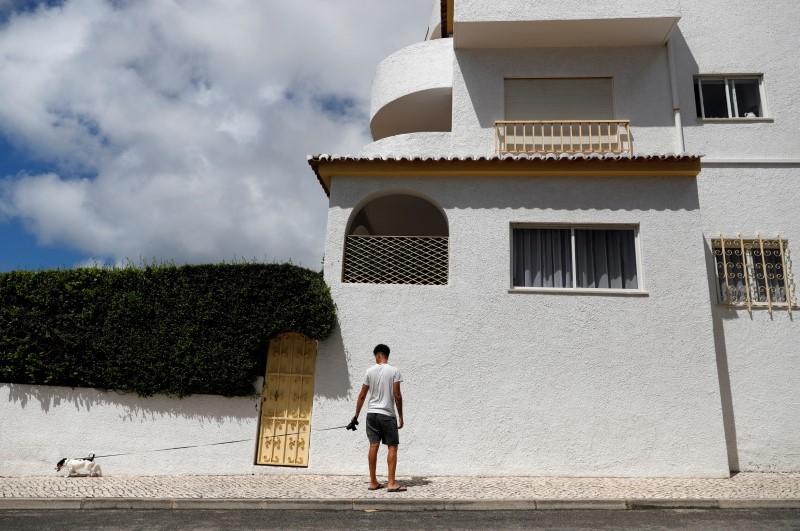 A man walks with his dog below the apartment where three-year-old Madeleine McCann disappeared in 2007, in Praia da Luz, Portugal, June 4, 2020. (Rafael Marchante/Reuters)