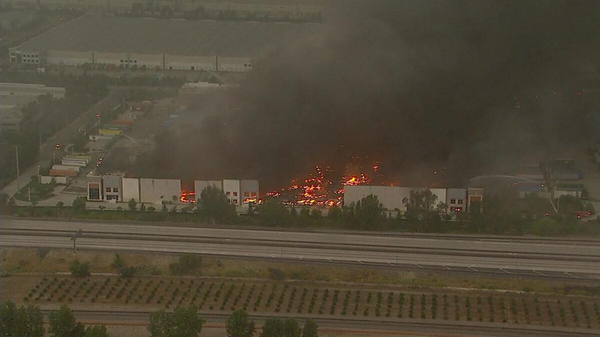 Thick plumes of smoke could be seen coming out of the warehouse that operates as an Amazon distribution center after it went up in flames after a three-alarm fire broke out, engulfing the entire building, in Redlands, Calif., on Jun. 5, 2020. (Courtesy of KABC)
