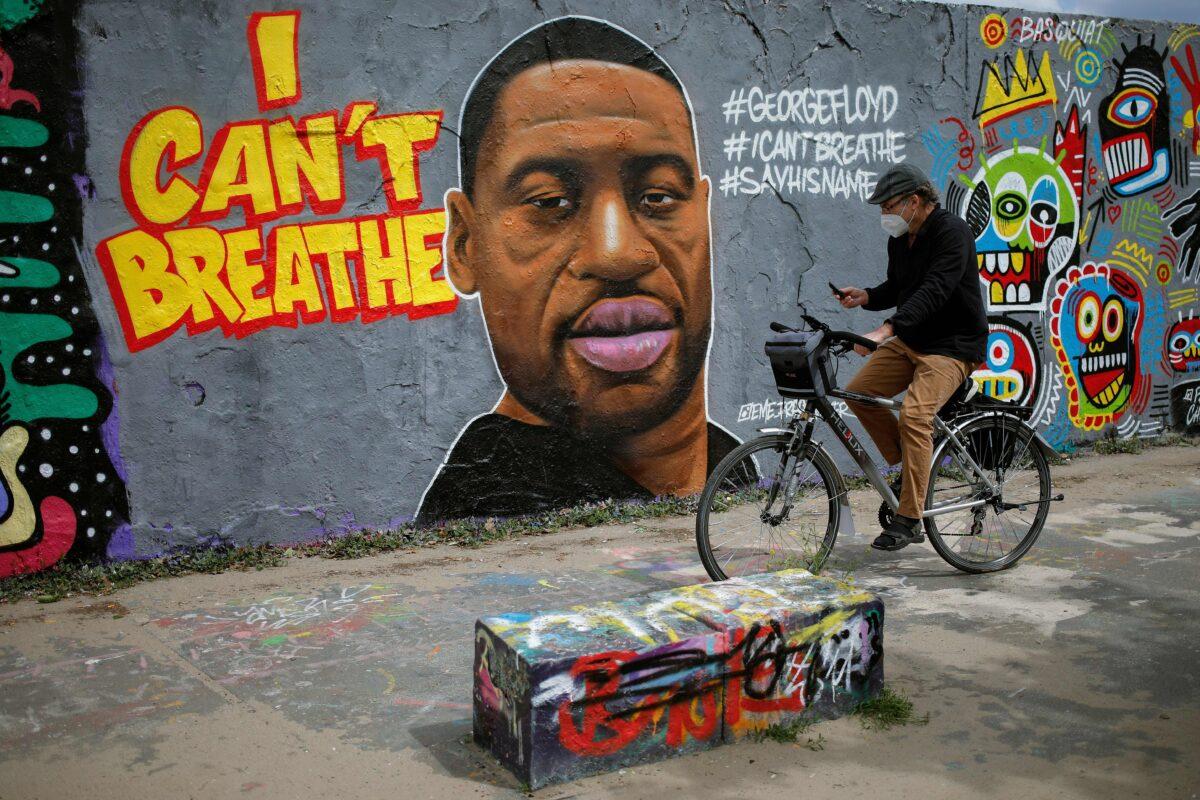 A man cycles past a mural depicting George Floyd, who died in Minneapolis in police custody, in Berlin, Germany, on May 30, 2020. (David Gannon/AFP/Getty Images)