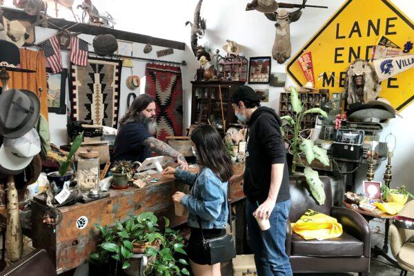 Matt De Vaul (L) shows customers one of the collectibles in his MMD Antiques shop in Old Towne Orange, Calif., on May 30, 2020. (Chris Karr/The Epoch Times)