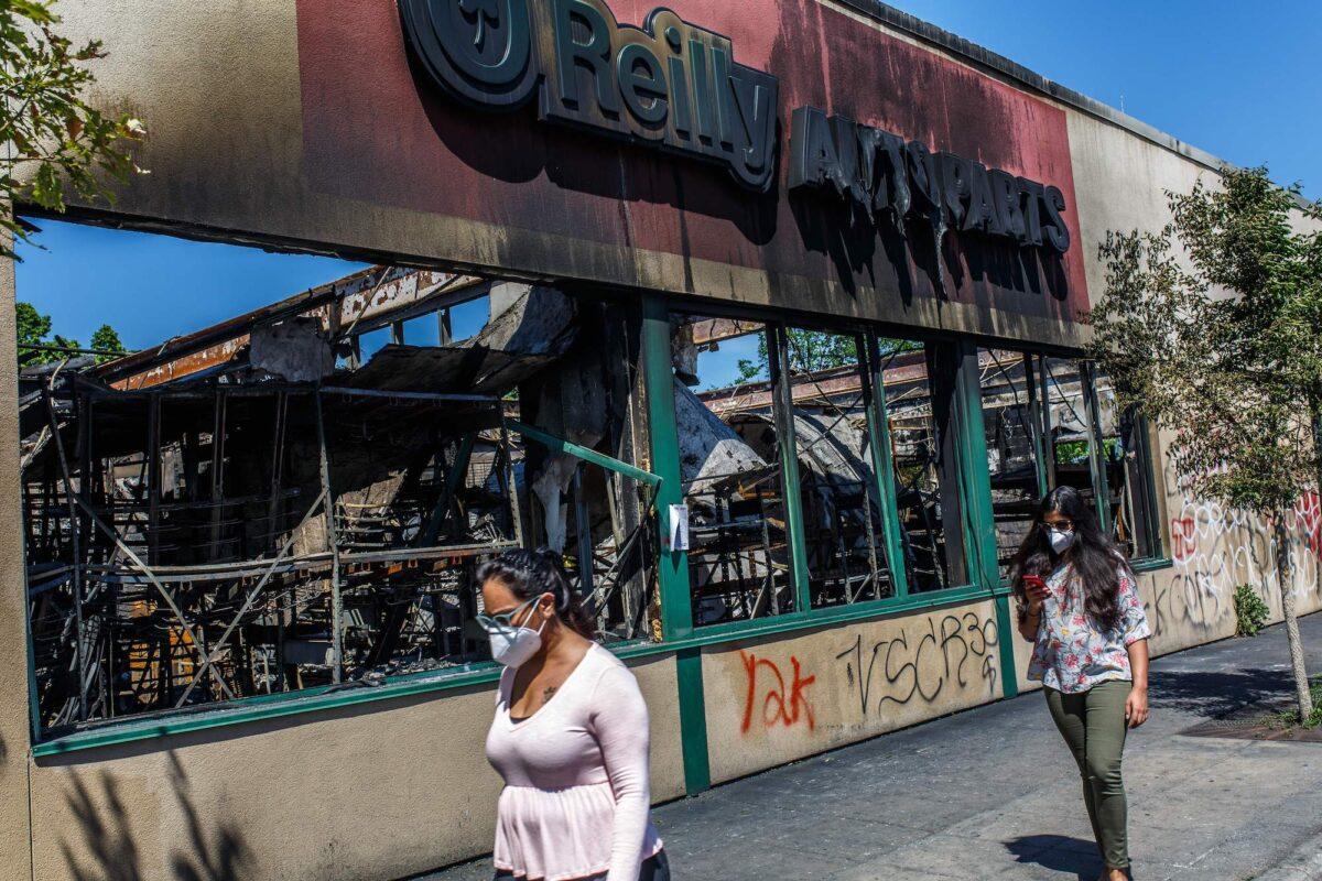 People walk past the charred wreckage of an auto parts store destroyed during last week's rioting, in Minneapolis, Minn., on June 3, 2020. (Kerem Yucel/AFP/Getty Images)