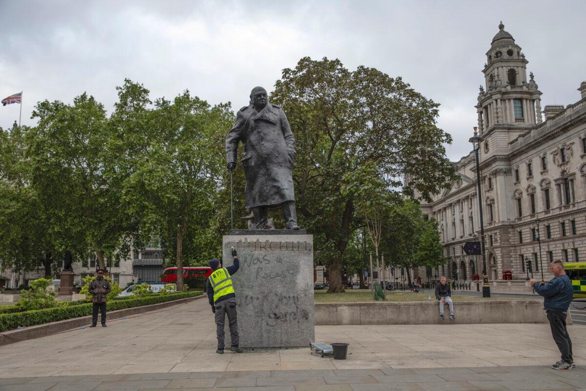 A worker cleans the defaced statue of Winston Churchill, which was spray painted with the words “was a racist,” in London, UK, on June 8, 2020. (Dan Kitwood/Getty Images)