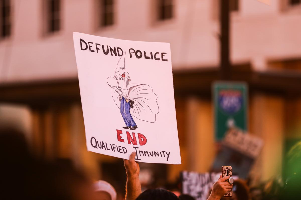 A “Defund the Police” sign is held up during a protest near the White House following the May 25 death of George Floyd in police custody, in Washington on June 6, 2020. (Charlotte Cuthbertson/The Epoch Times)