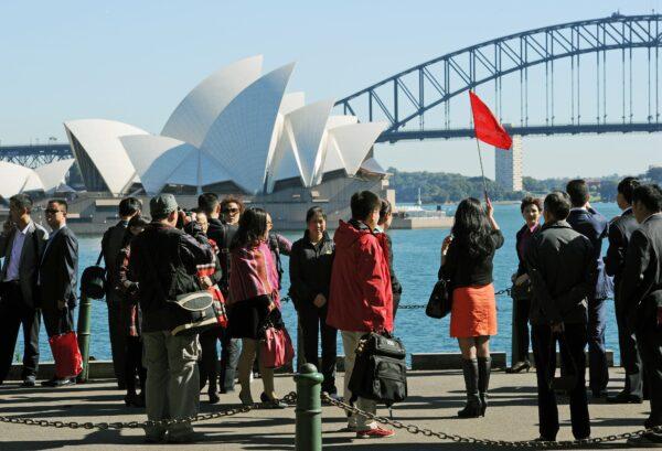 A group of Asian tourists has their photograph taken in front of the Sydney Opera House and Harbour Bridge on May 8, 2012. (Greg Wood/AFP/GettyImages)