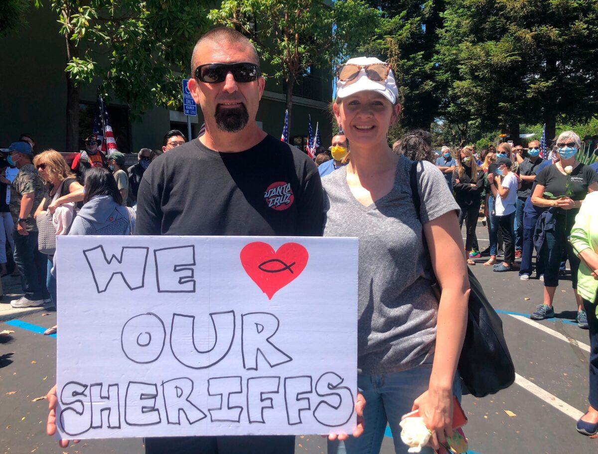 Jeff Dunworth and Erin Johnson of Santa Cruz joins more than a thousand people gather outside the Santa Cruz County Sheriff-Coroner's Office to pay their respects to fallen sheriff officer in Santa Cruz, Calif., on June 7, 2020. (Martha Mendoza/AP Photo)