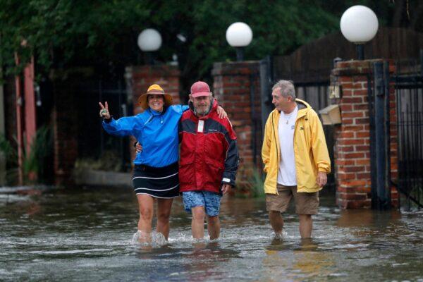 Isabelle Schneidau (L) gestures to the camera as she walks in a rising storm surge with Mont Echols (C) and L.G. Sullivan (R) after checking on their boats in the West End section of New Orleans in advance of Tropical Storm Cristobal in New Orleans, on June 7, 2020. (Gerald Herbert/AP Photo)