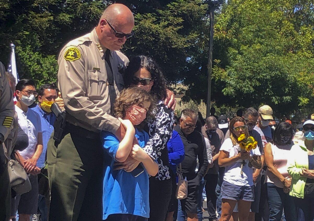 Santa Cruz Sheriff Jim Hart stands next to his wife and child, as more than a thousand people gather outside the Santa Cruz County Sheriff-Coroner's Office to pay their respects to fallen Sgt. Damon Gutzwiller in Santa Cruz, Calif., on June 7, 2020. (Martha Mendoza/AP Photo)