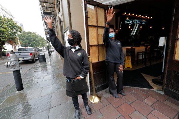 Destiny Patterson (L) and Jasmine Baquet, employees of the Royal House Restaurant, try to wave down customers in the largely deserted French Quarter of New Orleans in advance of Tropical Storm Cristobal La., on June 7, 2020. (Gerald Herbert/AP Photo)