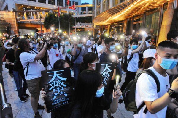People hold up their cellphones and placards with the words “Heaven Will Destroy the CCP” in a march in Central, Hong Kong, on June 9, 2020. (Song Bilong/The Epoch Times)