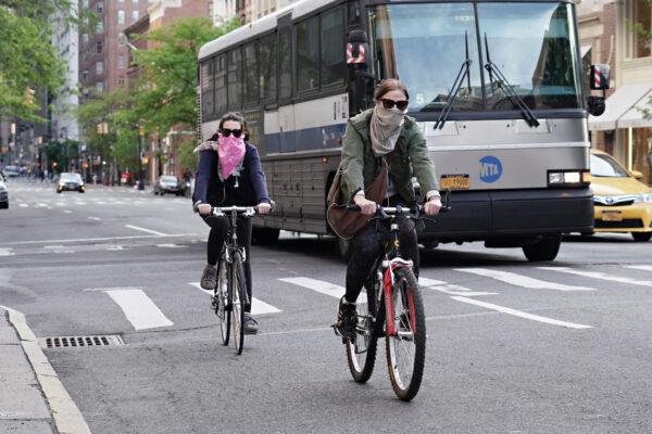 People ride bikes while wearing face coverings during the CCP virus pandemic in New York City, New York, on May 20, 2020. (Cindy Ord/Getty Images)